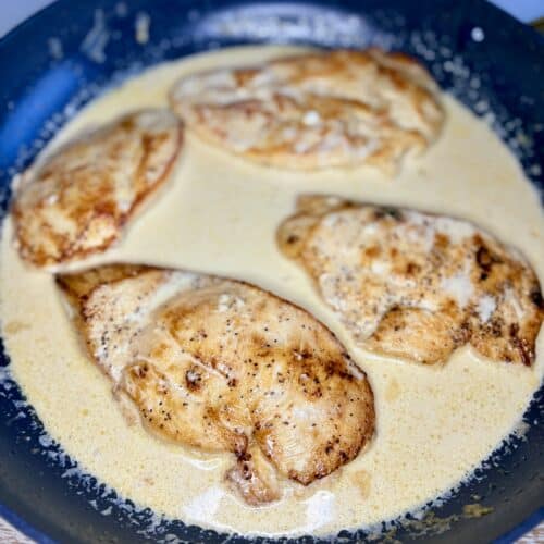 a skillet with cooked chicken in a creamy sauce