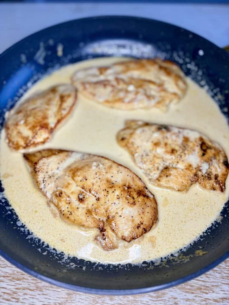 a skillet with cooked chicken in sauce