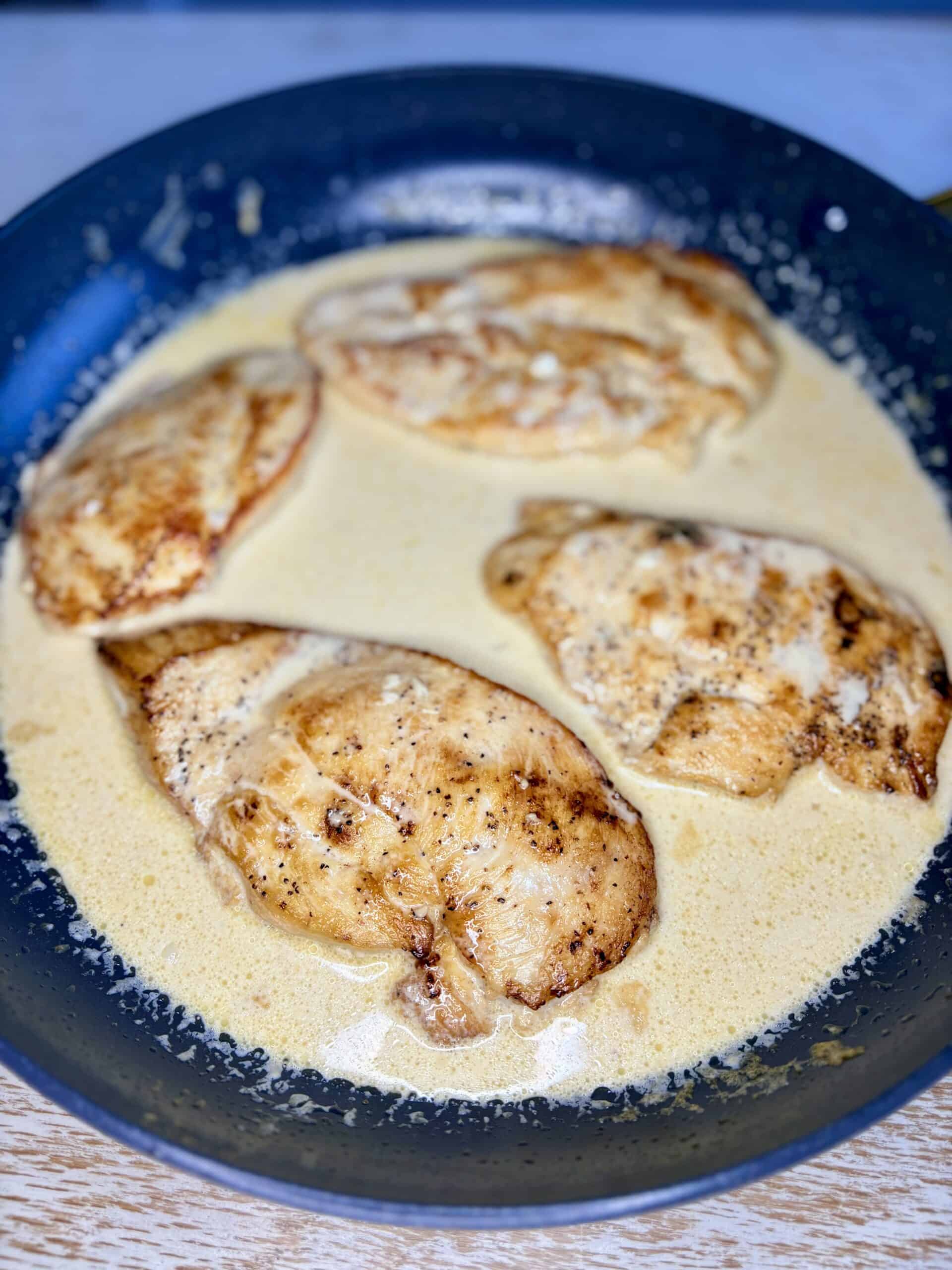 a skillet with cooked chicken in sauce