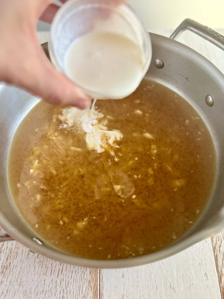 cream being poured in to a skillet with garlic, wine and broth