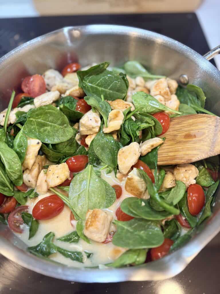 tomatoes, spinach and chicken warming in a skillet