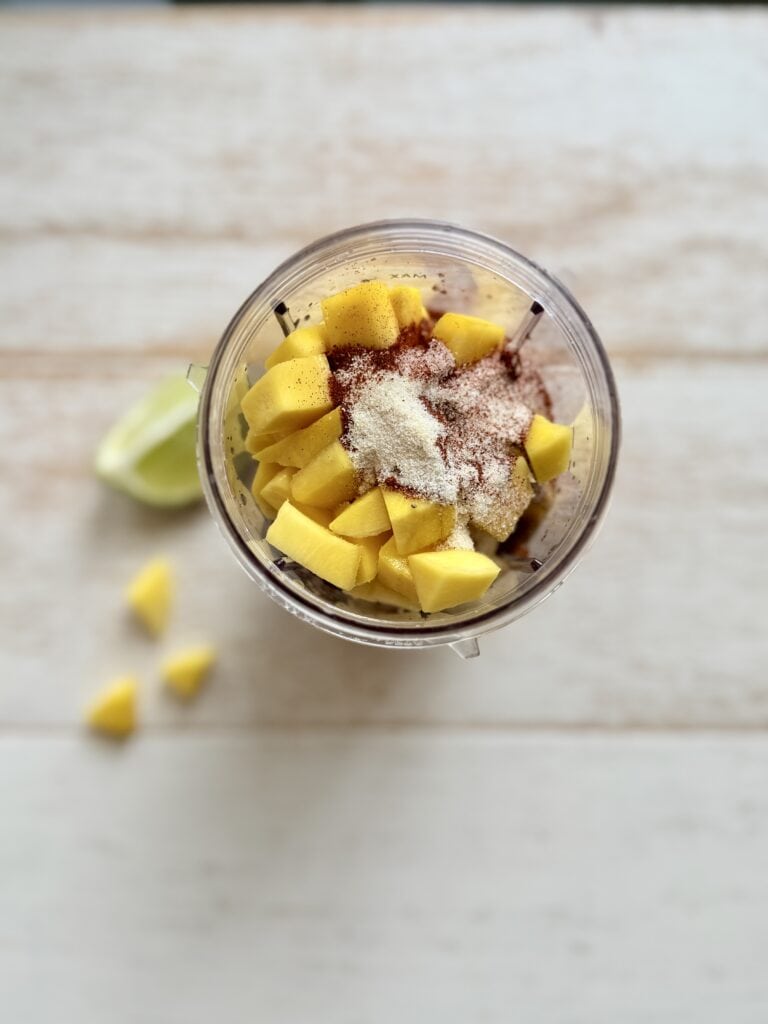 Mango bbq sauce ingredients in a plastic blender cup on the counter.