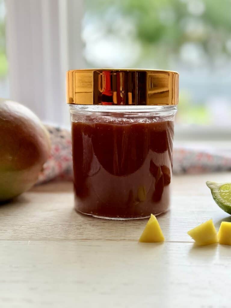 Mango bbq sauce in a mason jar with a copper lid on the counter.