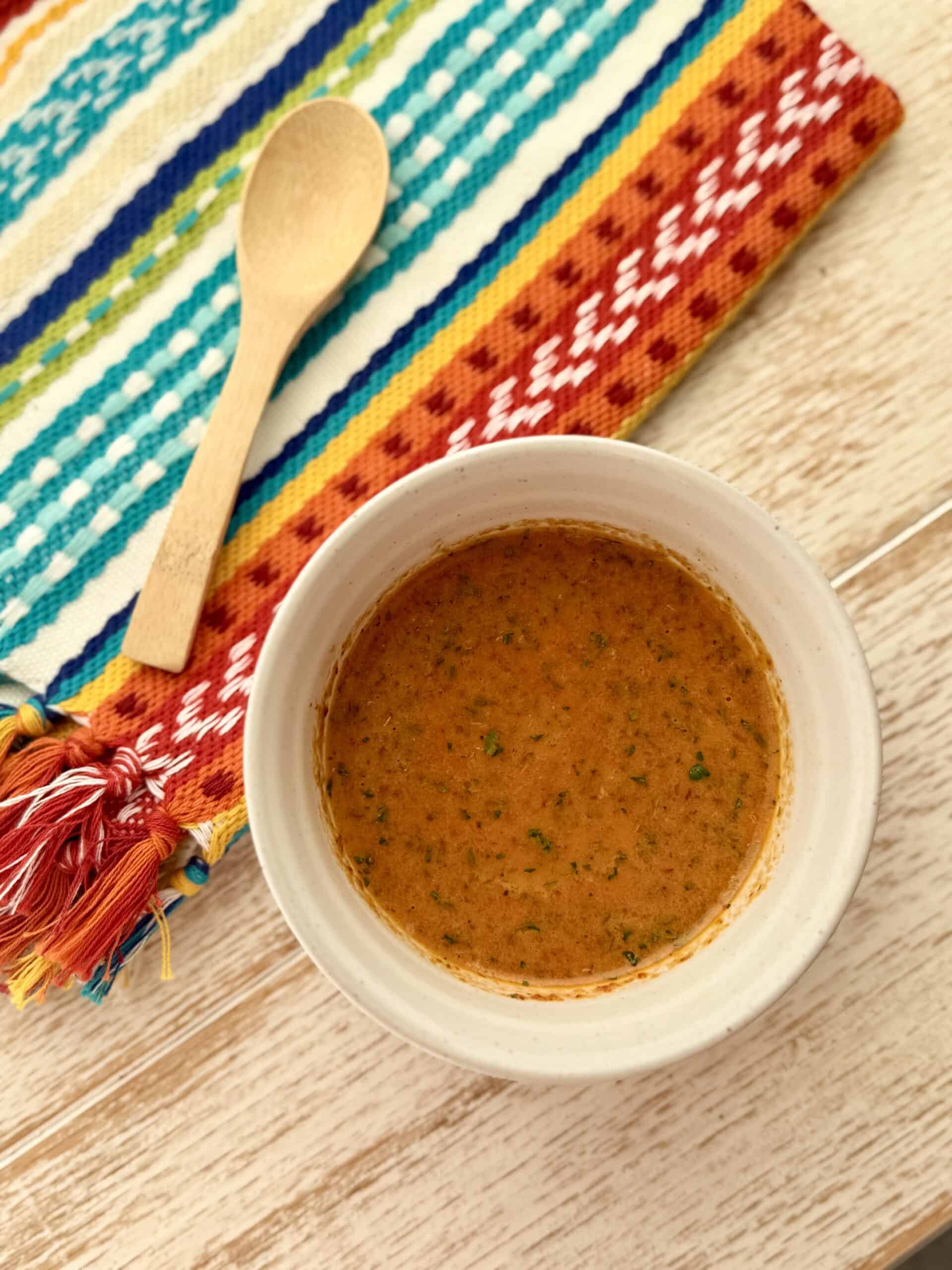Chipotle, honey vinaigrette, and a cream bowl on white counter with multicolored towel beside it with a small wooden spoon.