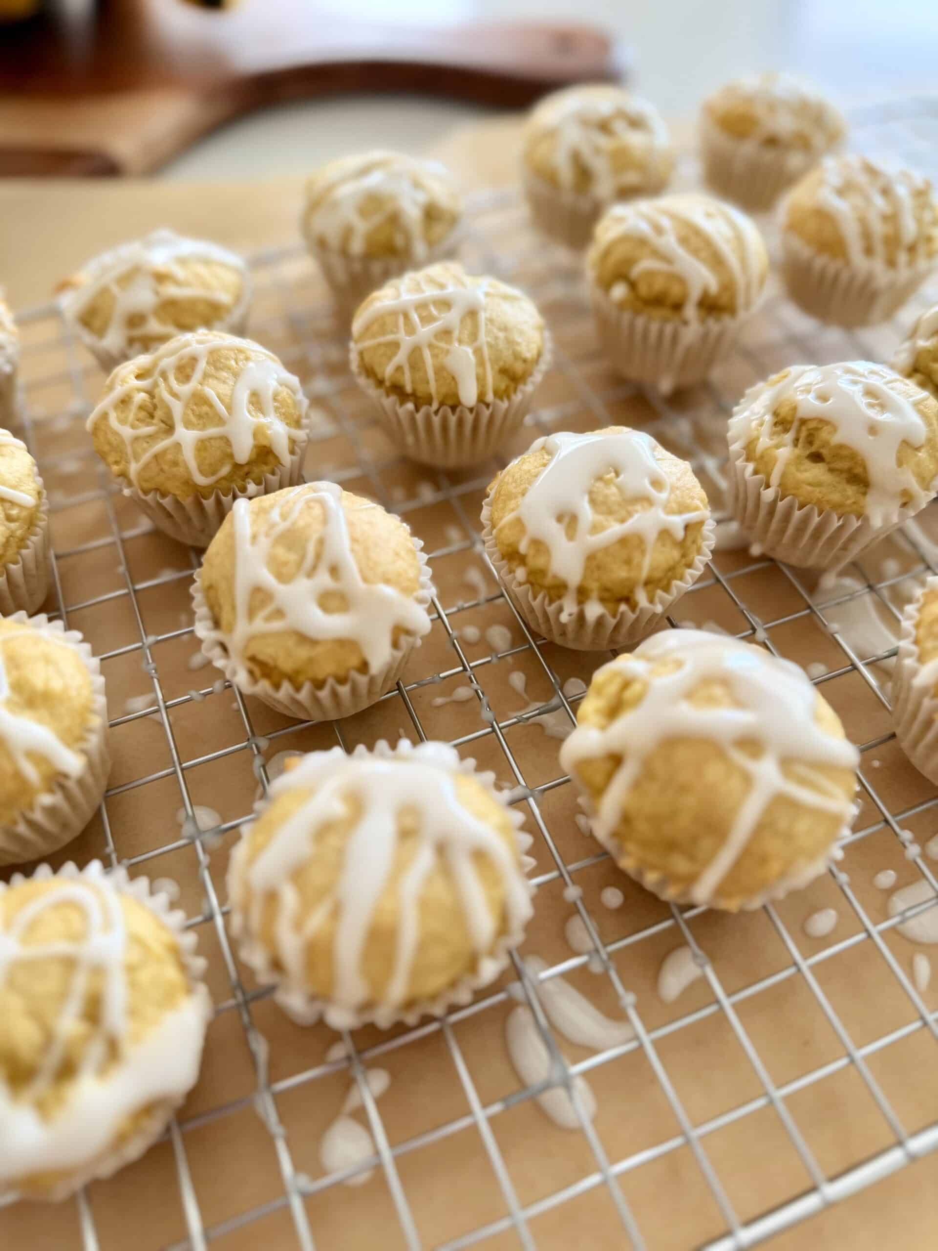 Mini banana muffins on a cooling rack on parchment paper on the counter.