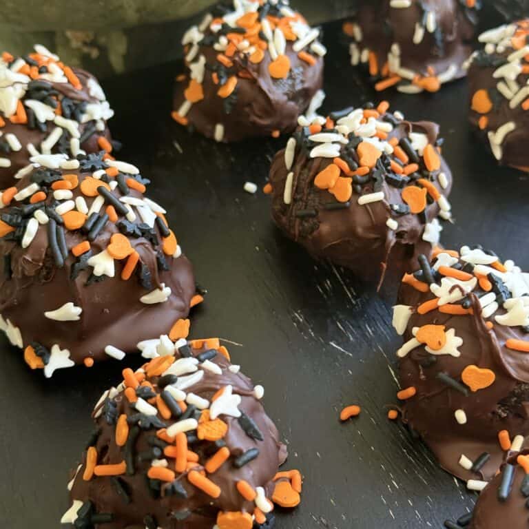 Rich chocolate dessert balls coated with colorful Halloween-themed sprinkles, perfect for festive celebrations and treats.