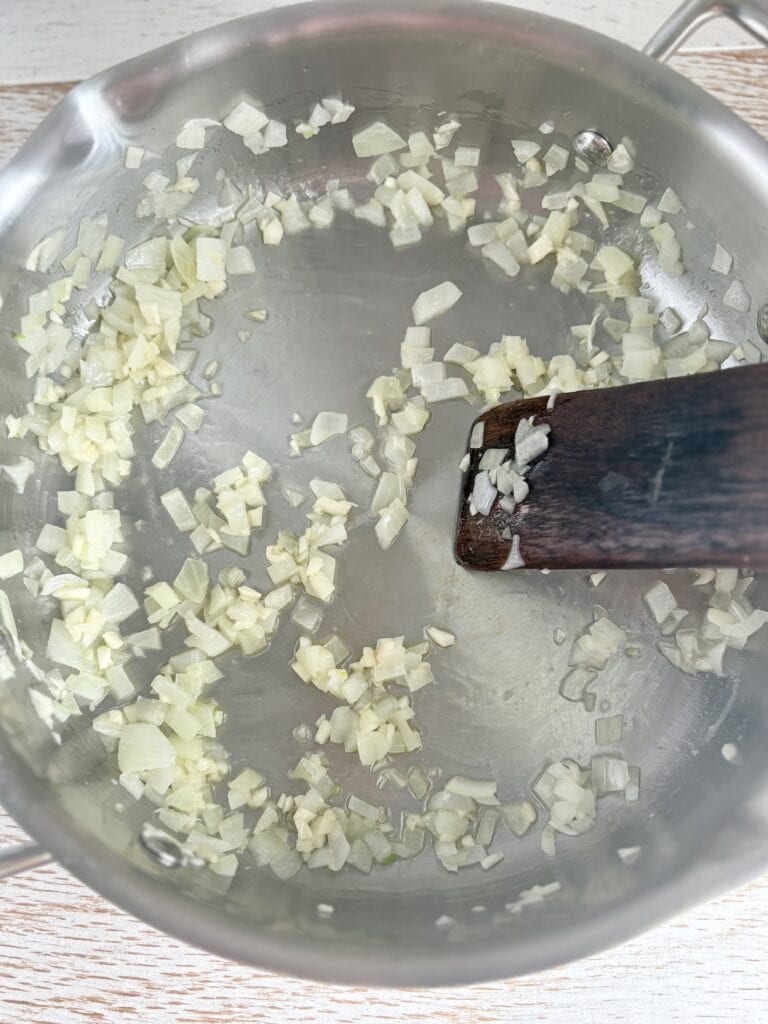 Minced onions sautéing in a stainless steel pan, perfect for cooking flavorful recipes and meal prep.