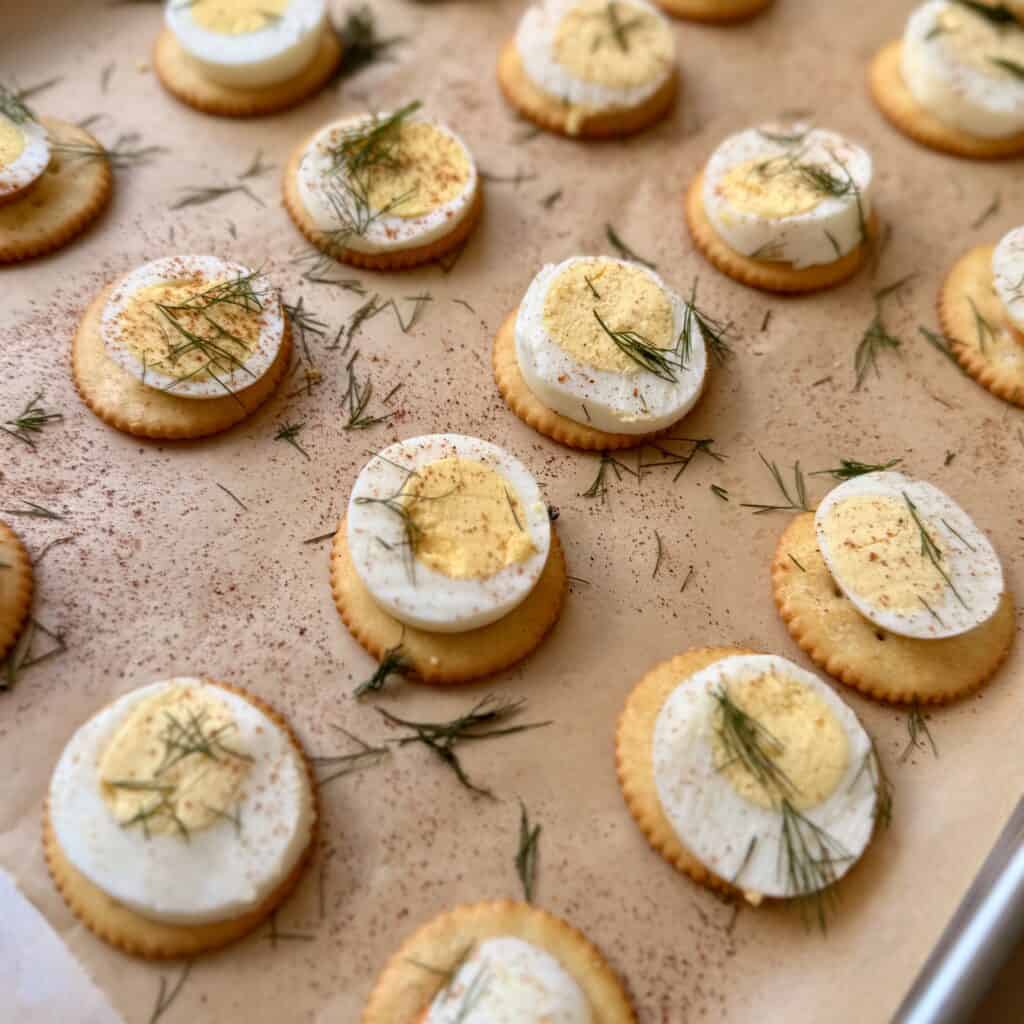Easy Deviled egg Bites garnished with fresh herbs on parchment paper, perfect for an appetizer or party tray.