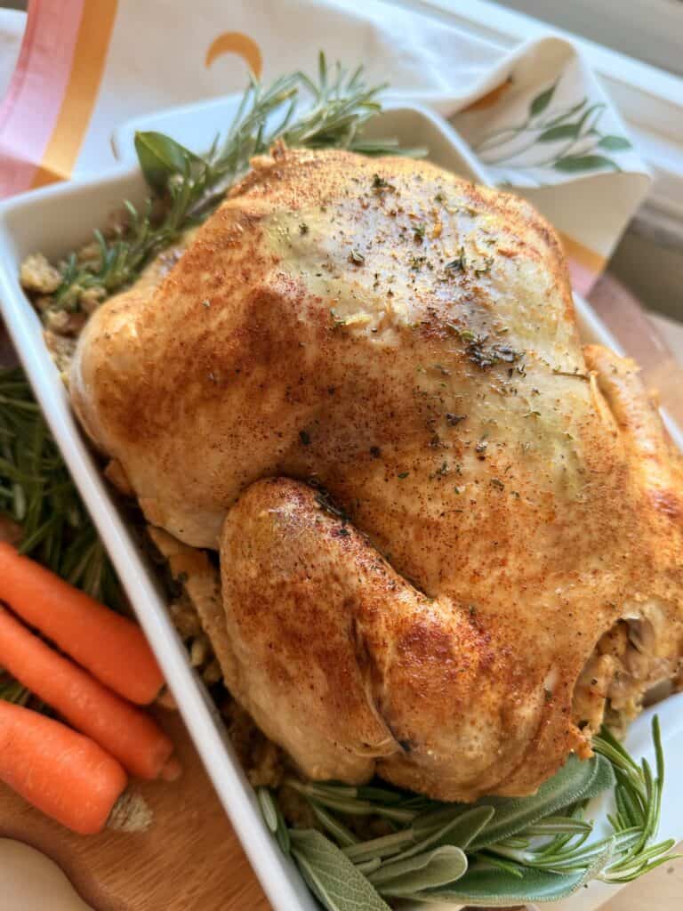 Juicy roasted chicken with crispy skin garnished with herbs, served with fresh carrots and herbs for a flavorful homemade dish.