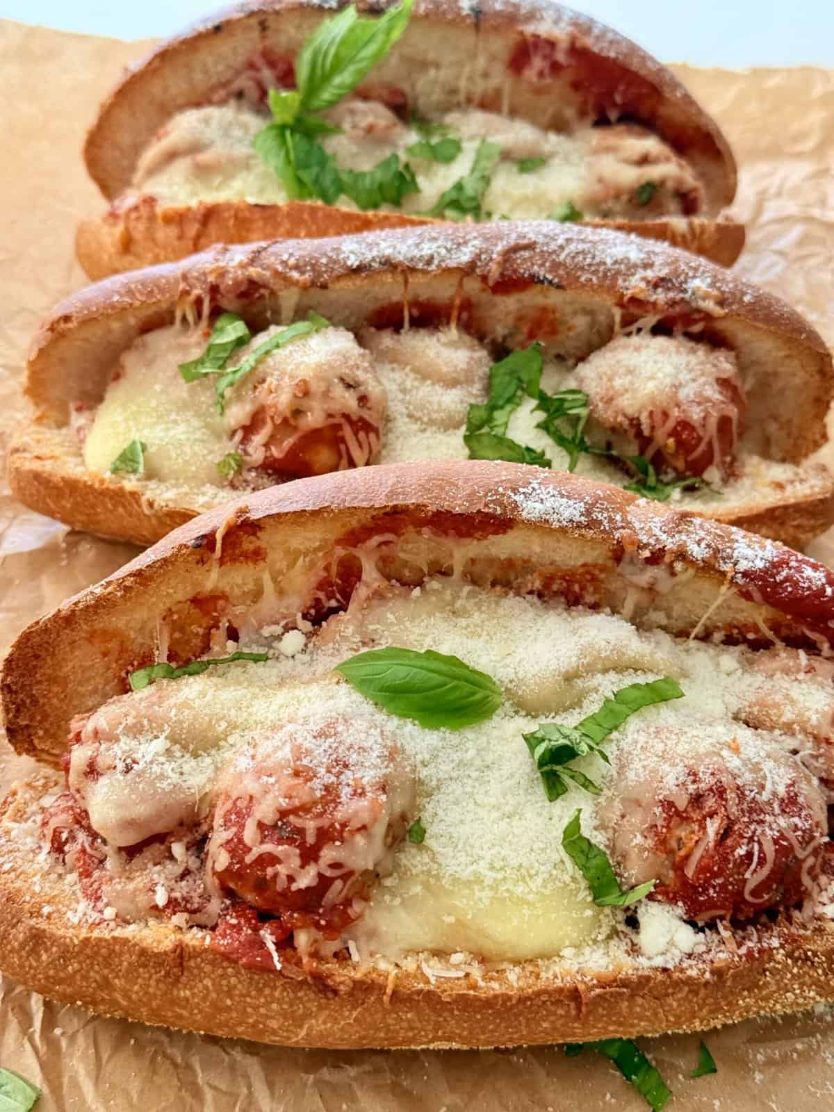 Savory meatball subs with melted cheese, fresh basil, and tomato sauce on toasted baguette slices, showcasing delicious comfort food perfect for lunch or dinner.