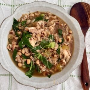 Savory chicken and vegetable soup with beans, greens, and herbs in a white bowl, perfect for cozy meals and healthy eating. Ideal for comfort food recipes, nutritious soups, and homemade dishes.
