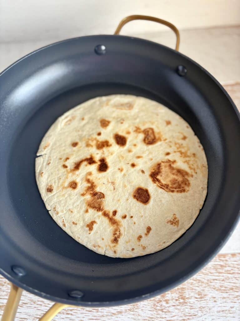 Delicious tortilla cooking in a black skillet, perfect for making fresh Mexican dishes like tacos and burritos.