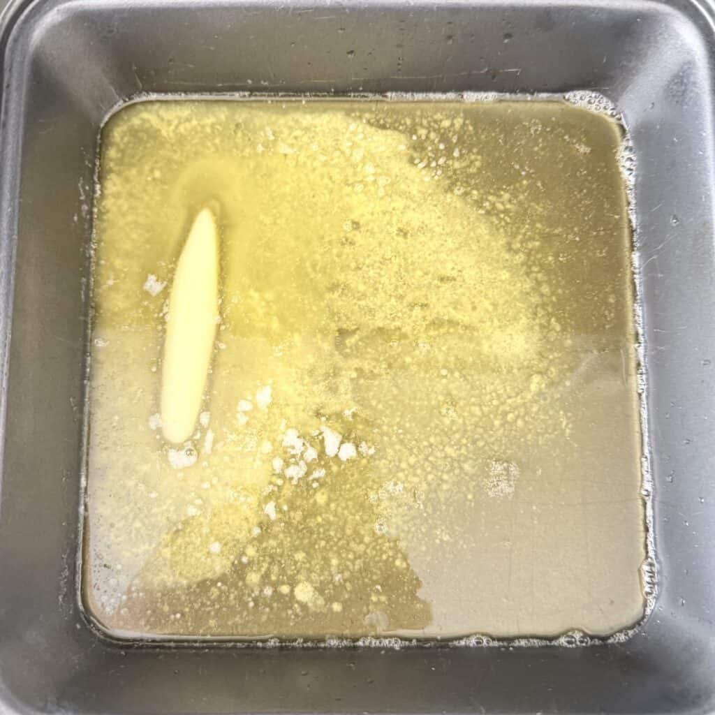 Melted unsalted butter in a 8 x 8 hot baking pan on the stovetop.