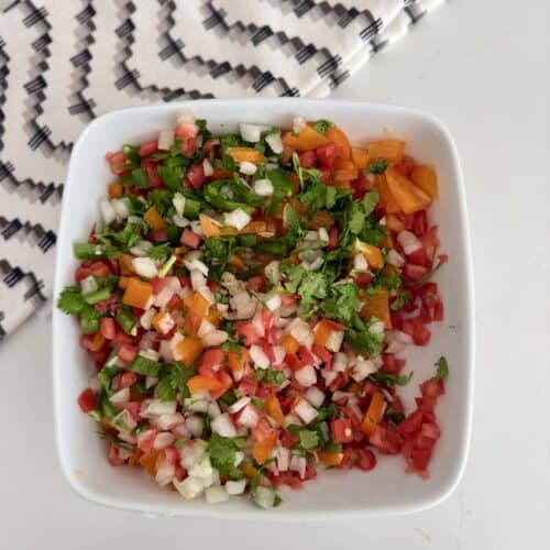 Fresh homemade pico de gallo with diced tomatoes, onions, jalapeños, cilantro, and lime in a white bowl. Perfect for tacos, chips, or as a flavorful topping.