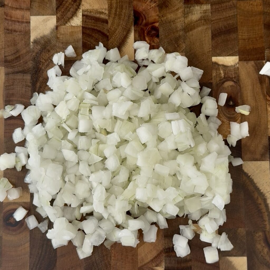 Diced white onion pieces on a brown cutting board