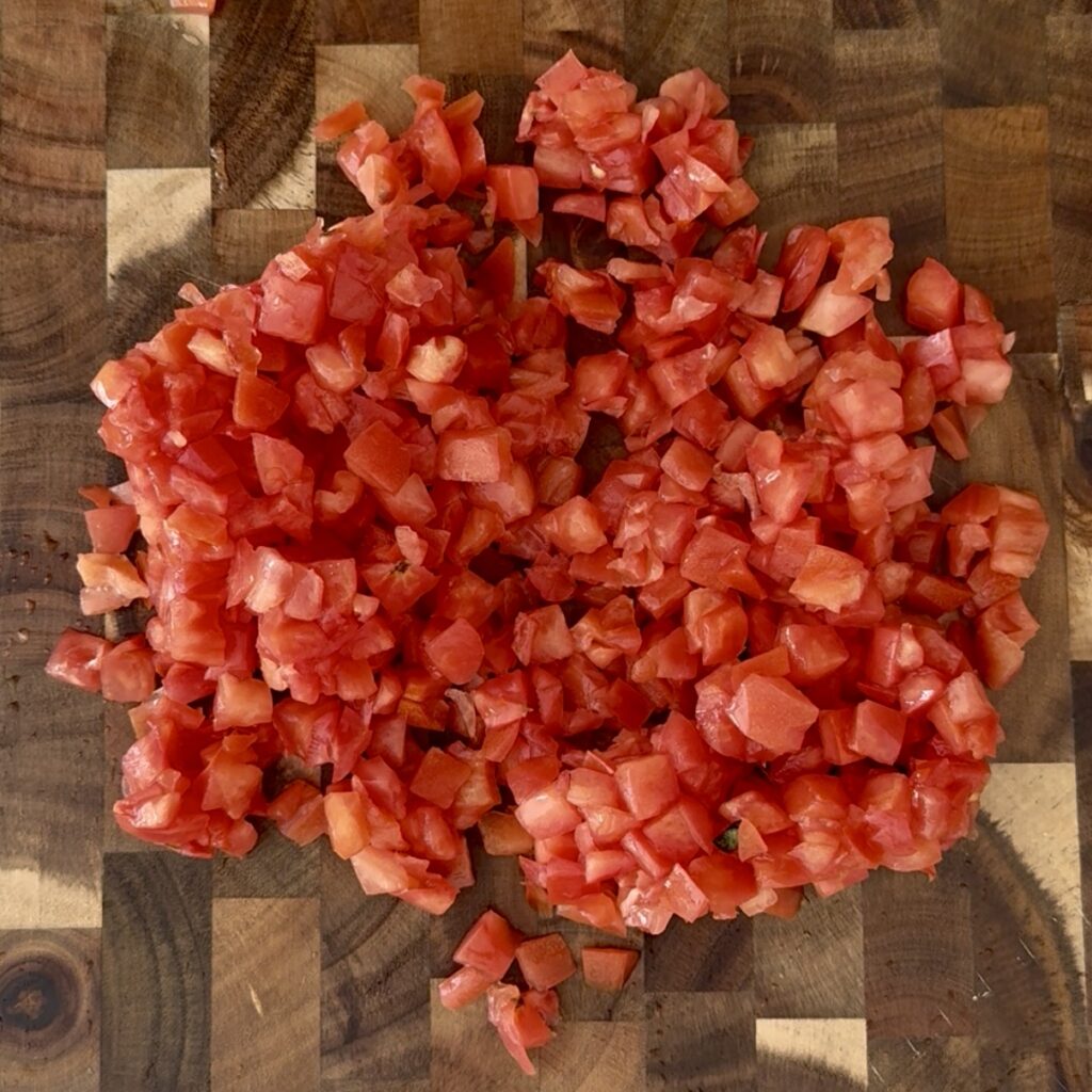 Diced tomato pieces on a brown cutting board