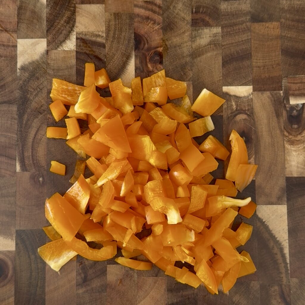 Tasted yellow pepper pieces on a brown cutting board