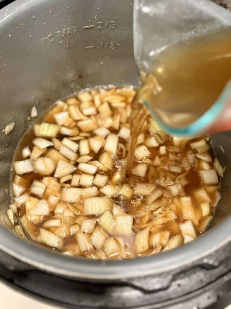 diced onions and broth in a pot, ready for beef to be added for flautas
