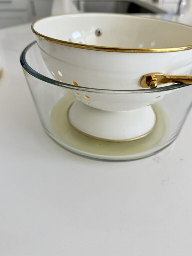 Draining excess liquid from thawed mangoes in a colander