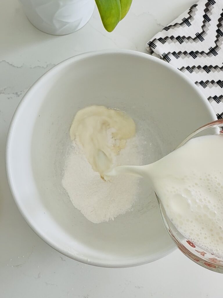 pouring milk into a white bowl with instant cheesecake pudding mix.