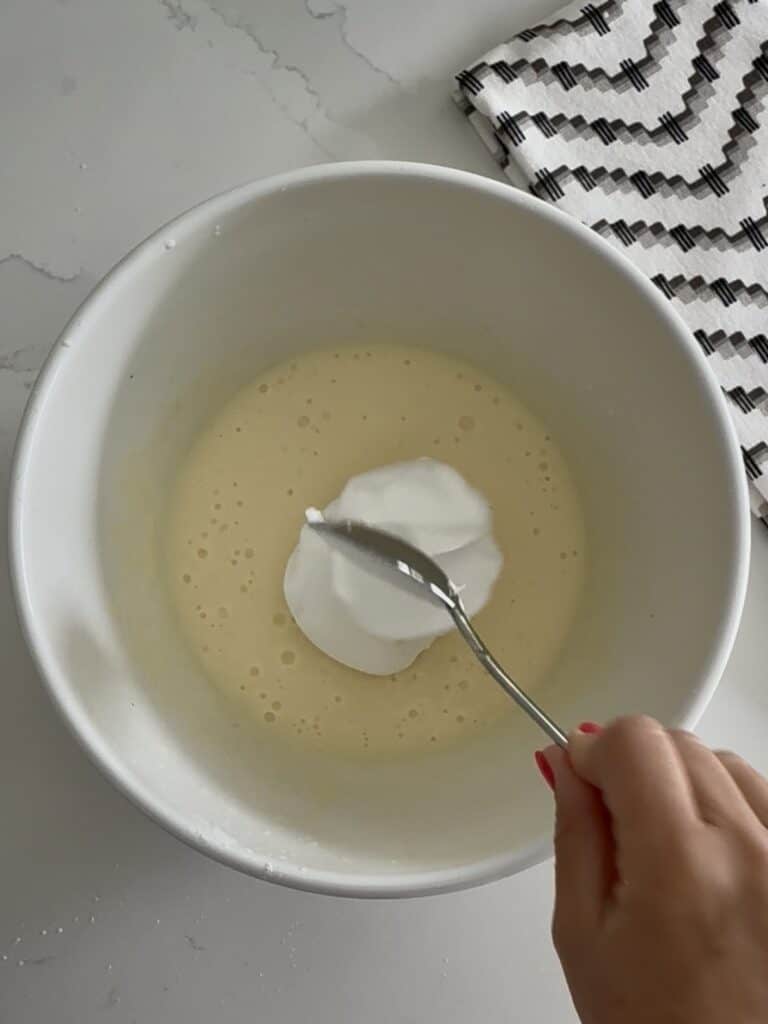 Place Cool Whip into the instant cheesecake pudding. all in a white bowl on the counter