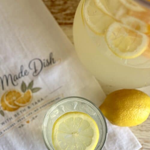 Refreshing citrus vodka lemonade in a pitcher with lemon slices and a glass with lemon slices, perfect for summer drinks.