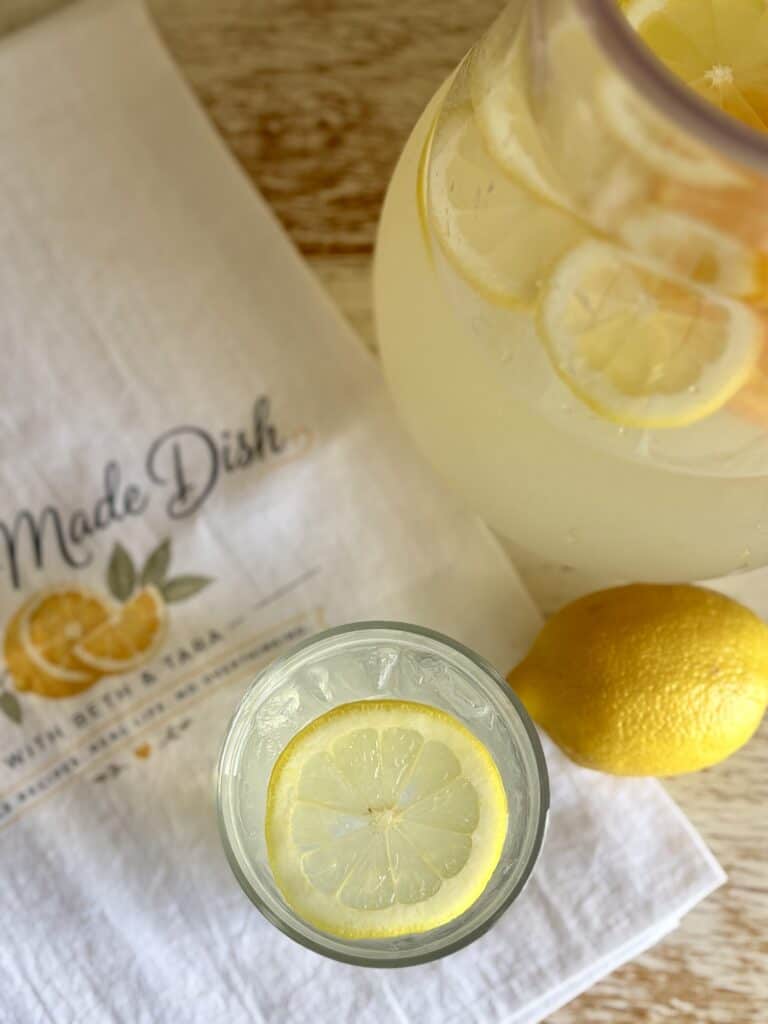 Refreshing citrus vodka lemonade in a pitcher with lemon slices and a glass with lemon slices, perfect for summer drinks.