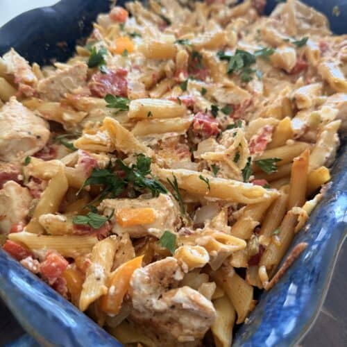 Delicious chicken fajita penne pasta with colorful vegetables and herbs in a blue baking dish, perfect for a flavorful meal.
