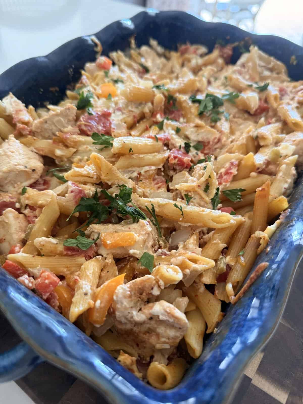 Delicious chicken fajita penne pasta with colorful vegetables and herbs in a blue baking dish, perfect for a flavorful meal.