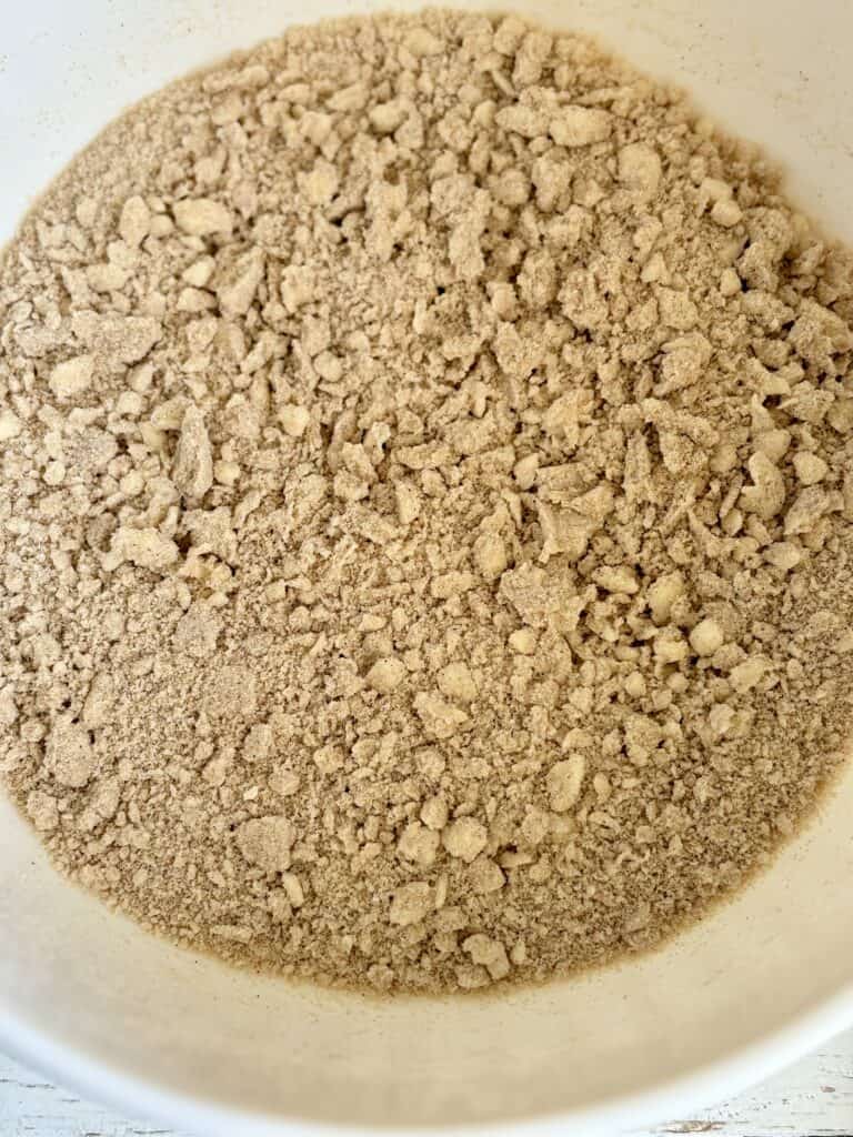Cinnamon streusel topping with coarse crumbs and larger clumps in a white bowl.