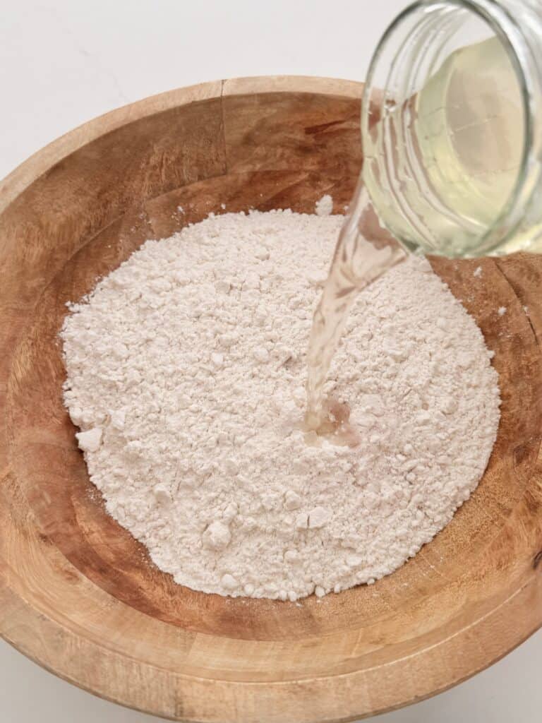 Honey and warm water being poured into the flour mixture.