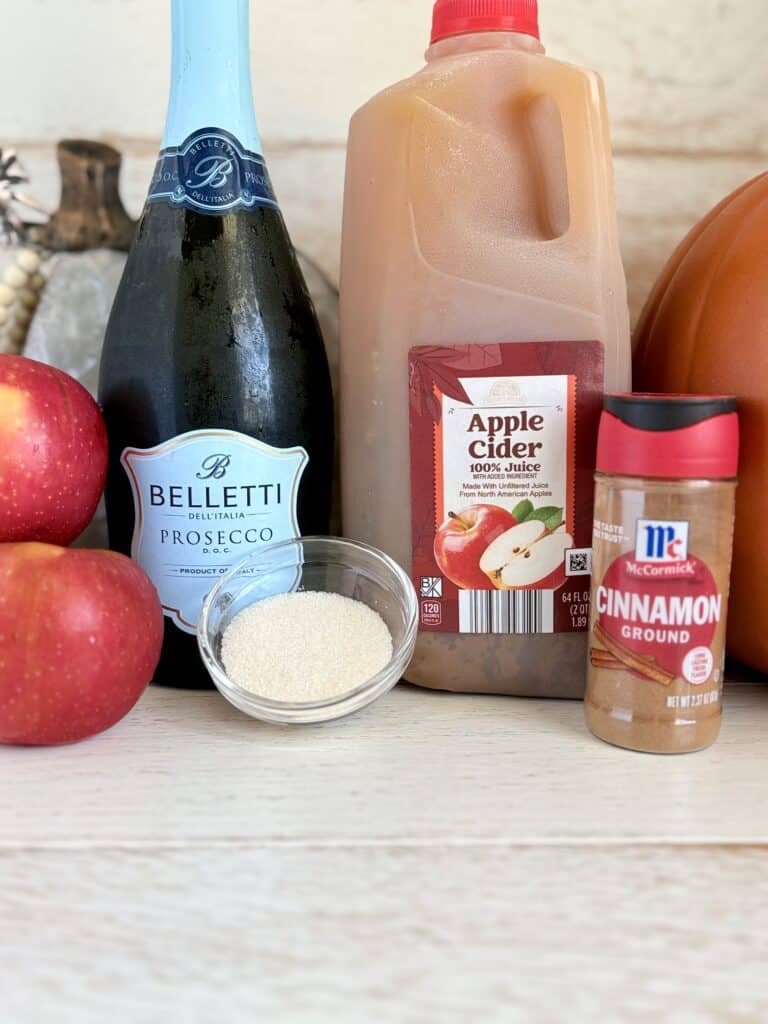 Ingredients for Apple Cider Spritz on a wooden board with fall decorations.