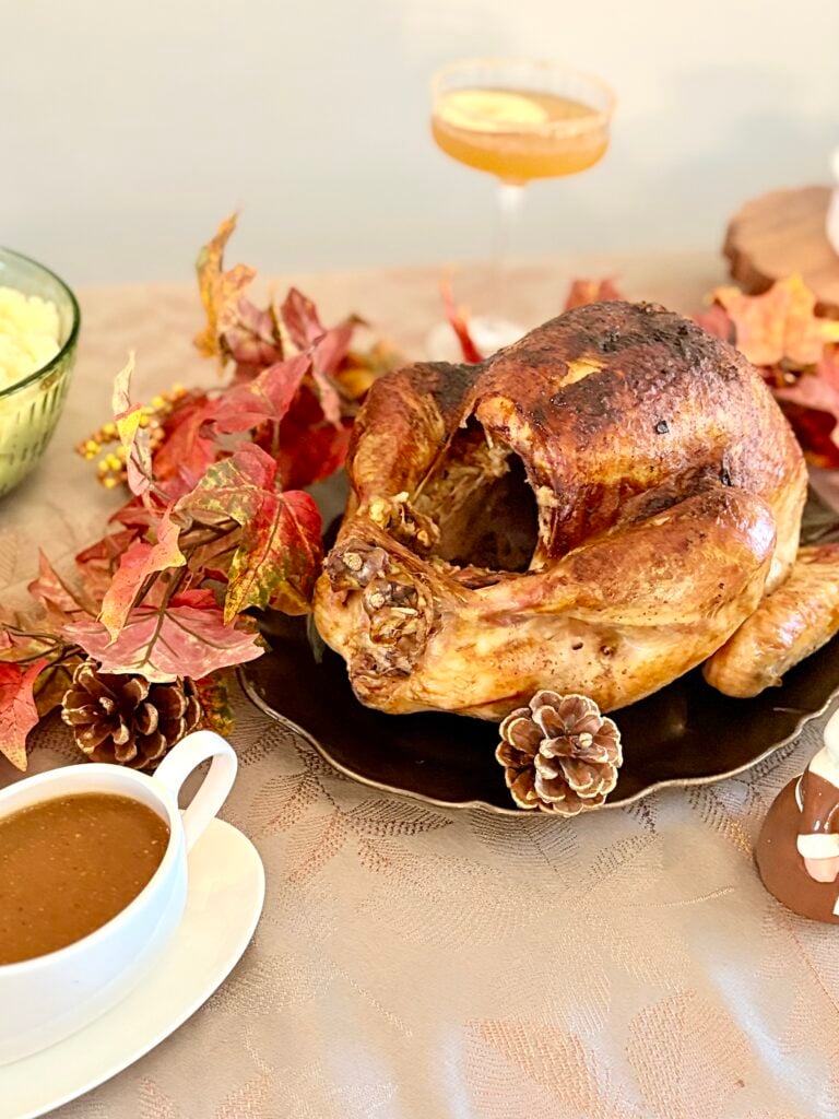 Juicy roasted turkey with golden-brown skin served on a festive table with autumn leaves and traditional sides.