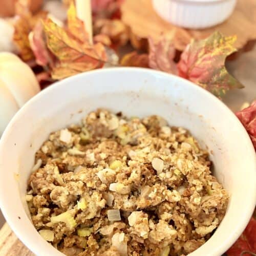 Close-up of homemade stuffing in a white bowl with herbs and vegetables, perfect for Thanksgiving dinner.