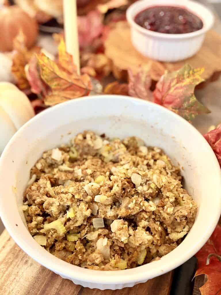 Close-up of homemade stuffing in a white bowl with herbs and vegetables, perfect for Thanksgiving dinner.