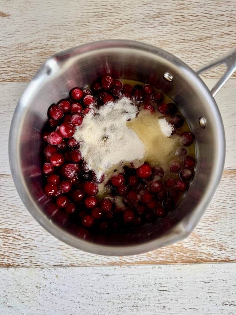 Fresh cranberries in a saucepan with sugar and orange juice, ready to be cooked into a delicious cranberry sauce for holiday meals.
